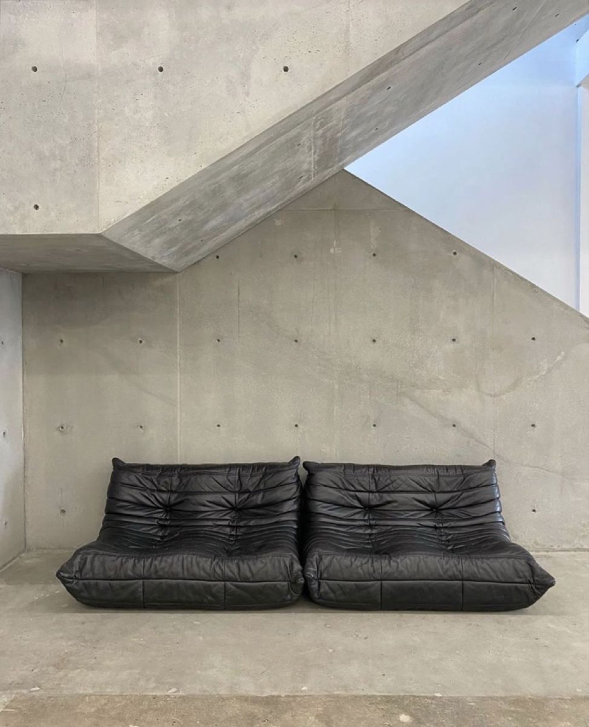 A black leather Togo against raw board-formed concrete
